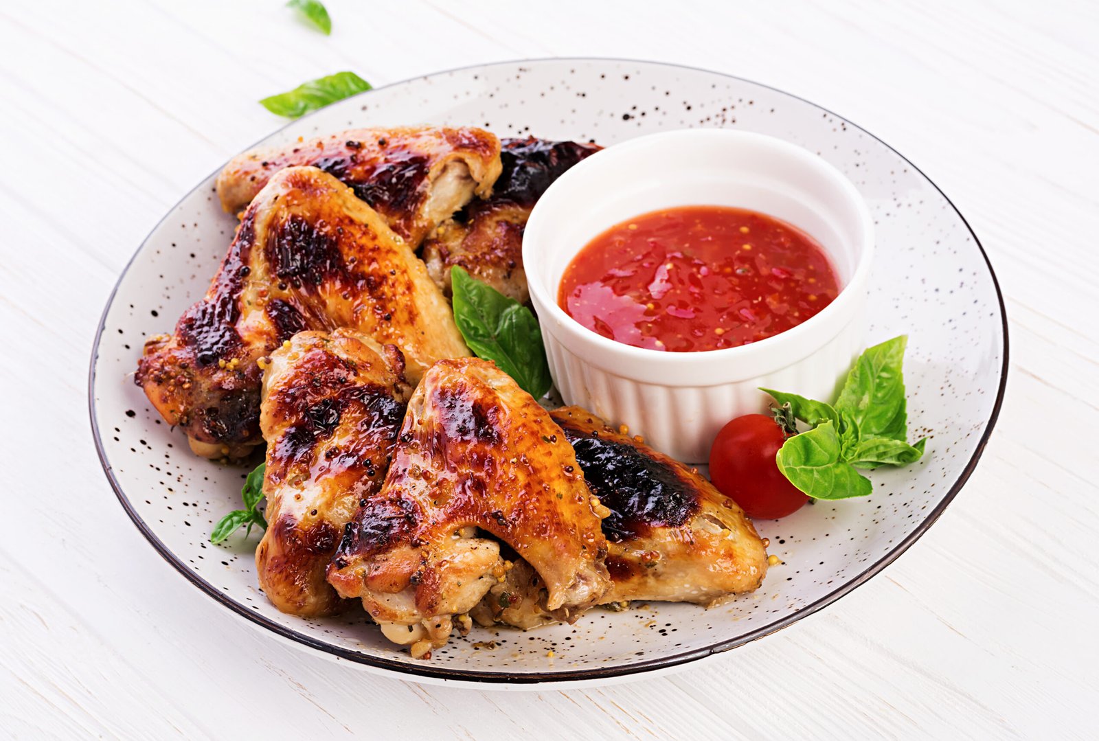Baked chicken wings in the Asian style and tomatoes sauce on plate